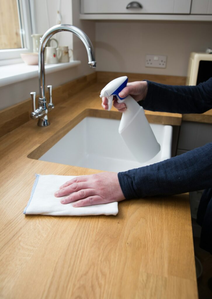 A housewife doing housework and cleaning a kitchen work surface with a disinfectant spray and cloth