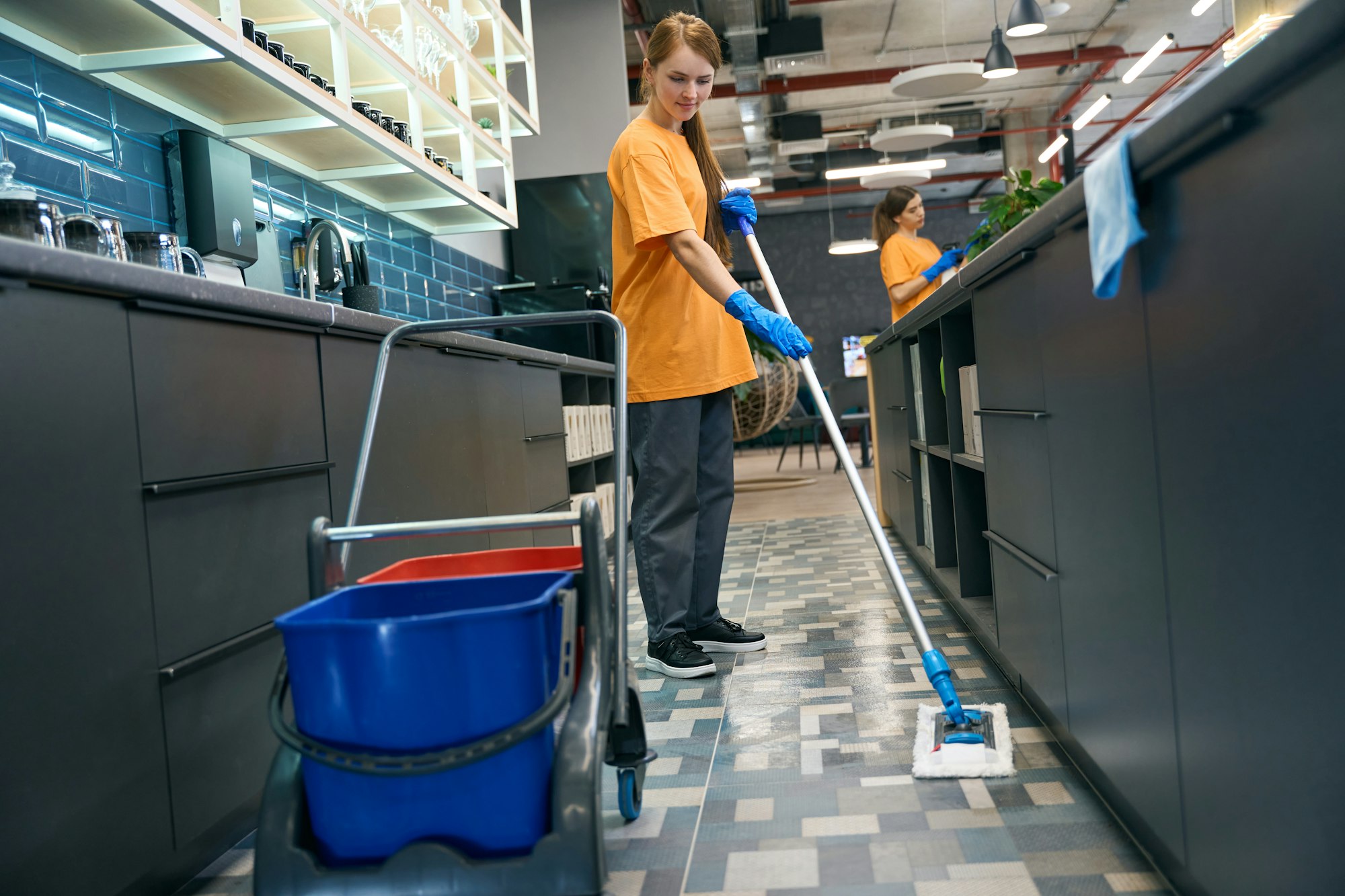 Young woman cleaning the floor with a mop