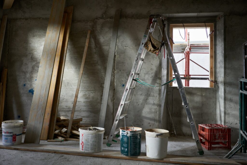 Room under construction with a ladder and paint buckets before cleanup