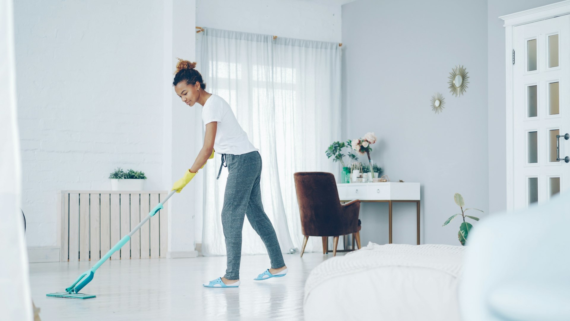 Housekeeper mopping a bright living room floor during a house cleaning