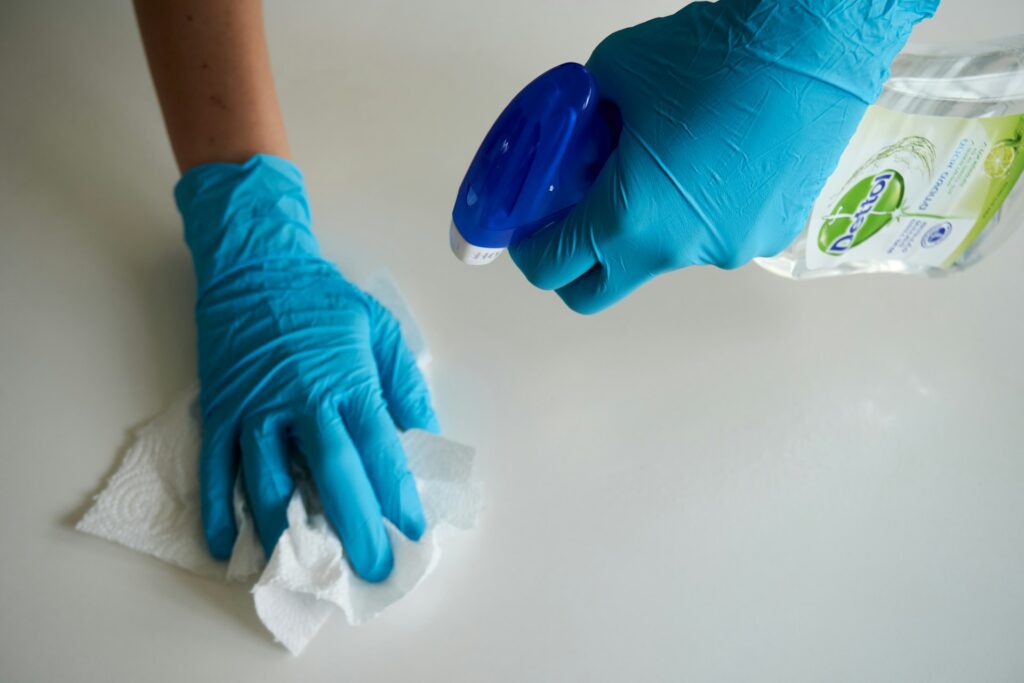 Gloved hand wiping and disinfecting a white kitchen counter